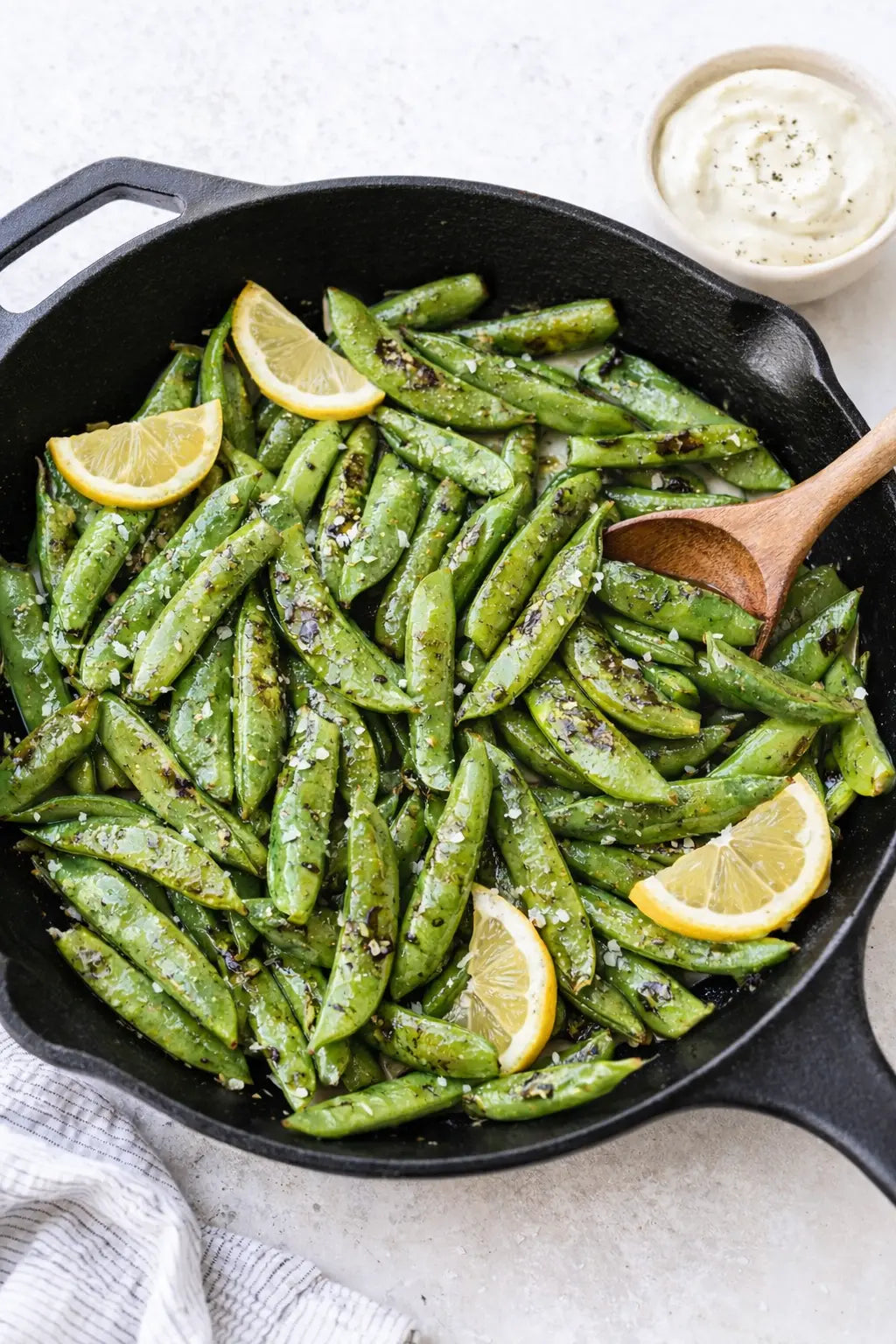 Blistered sugar snap peas in a cast iron skillet with lemon