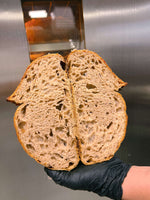 Close-up of freshly baked bread, sliced in half to reveal its soft, airy texture against a metallic background.